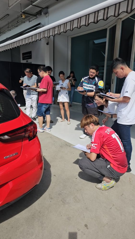 Hands-on Igive automotive training with participants inspecting a vehicle outdoors.